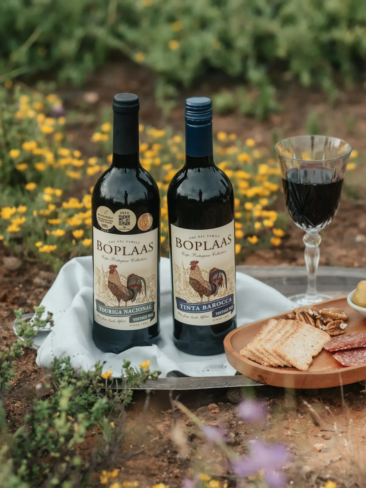 Boplaas wines on a picnic table among wild flowers, photographed by Web Brew